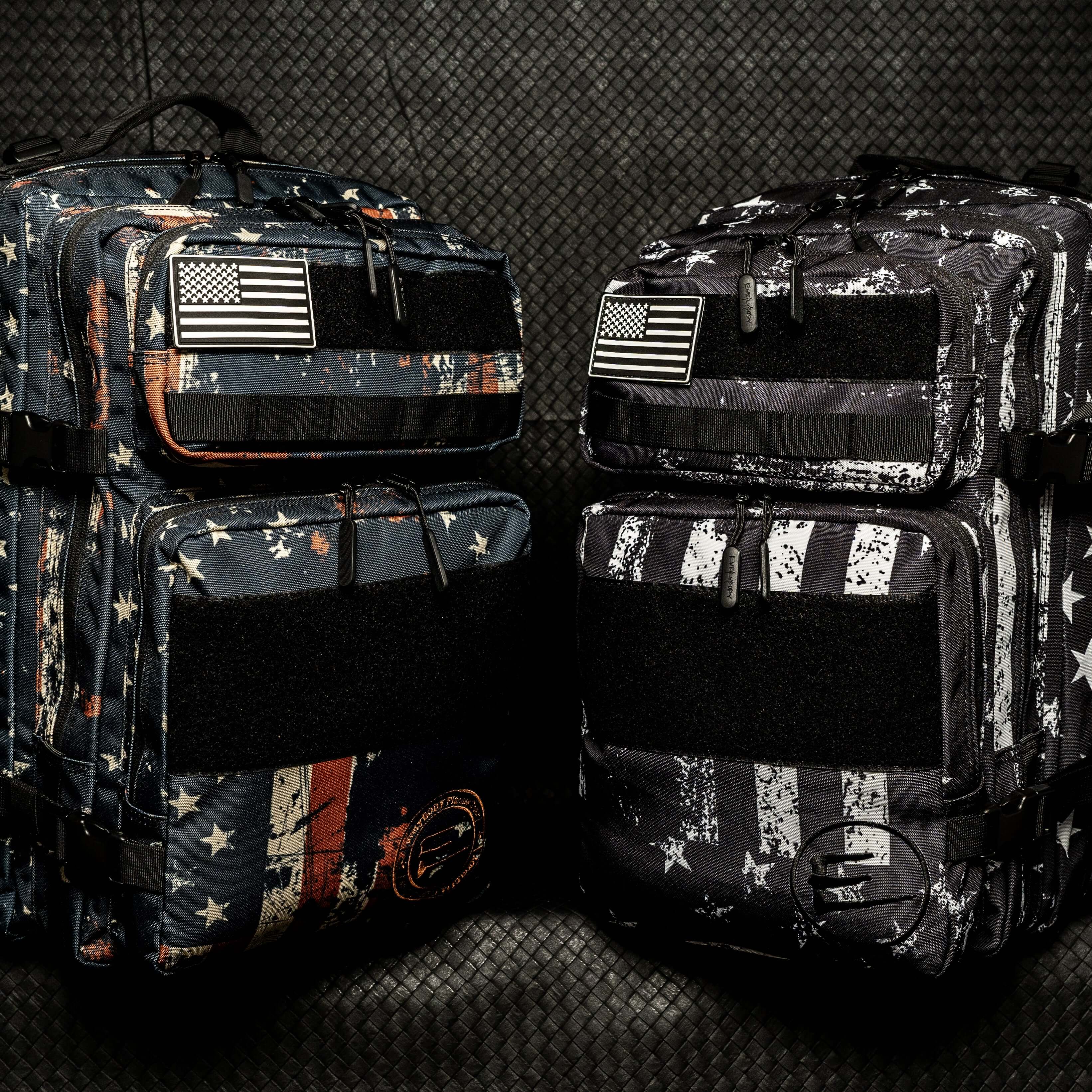45L Black American Flag Backpack with Cup Holder sitting beside a blue American flag backpack.