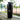 Black 26 oz Stainless Steel Shaker Bottle on bleachers near a baseball field.