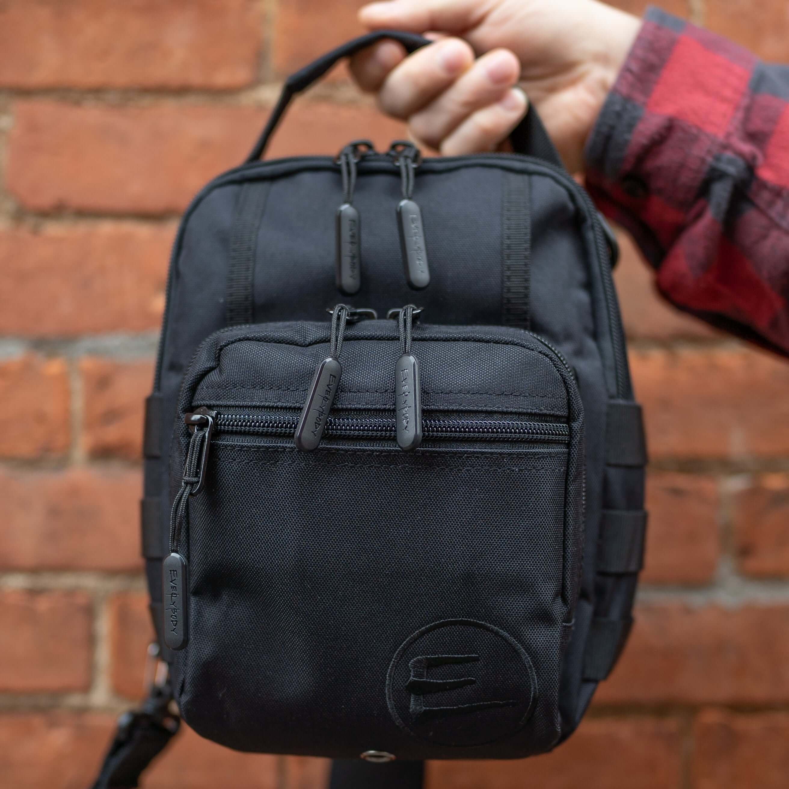 12L Black Athletic Crossbody Bag being held up by a male model.