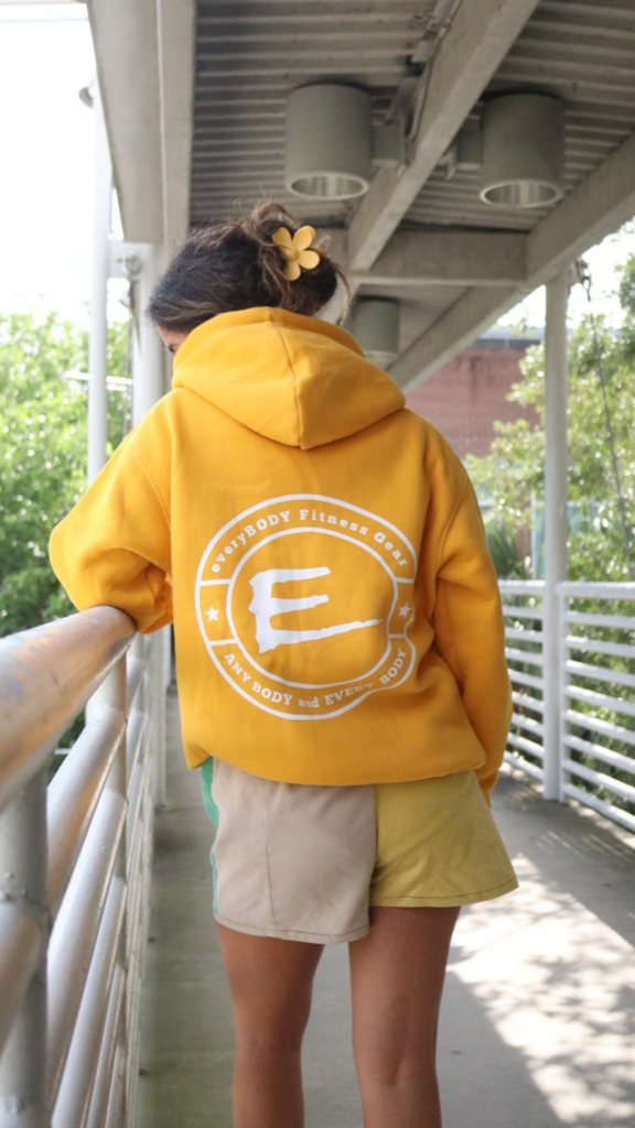 Model wearing yellow unisex logo hoodie